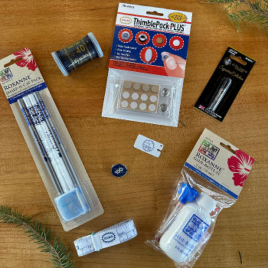 Collection of sewing supplies including thread, needles, and packaging on a wooden surface.